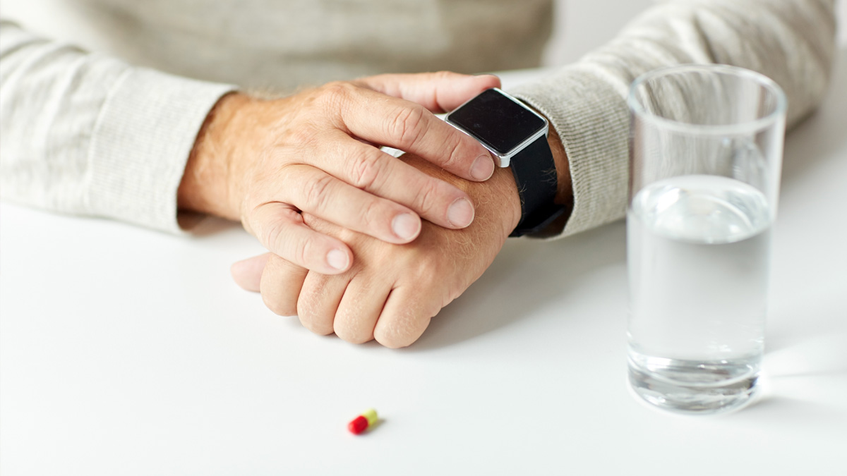 Comprimido, vaso de agua y reloj